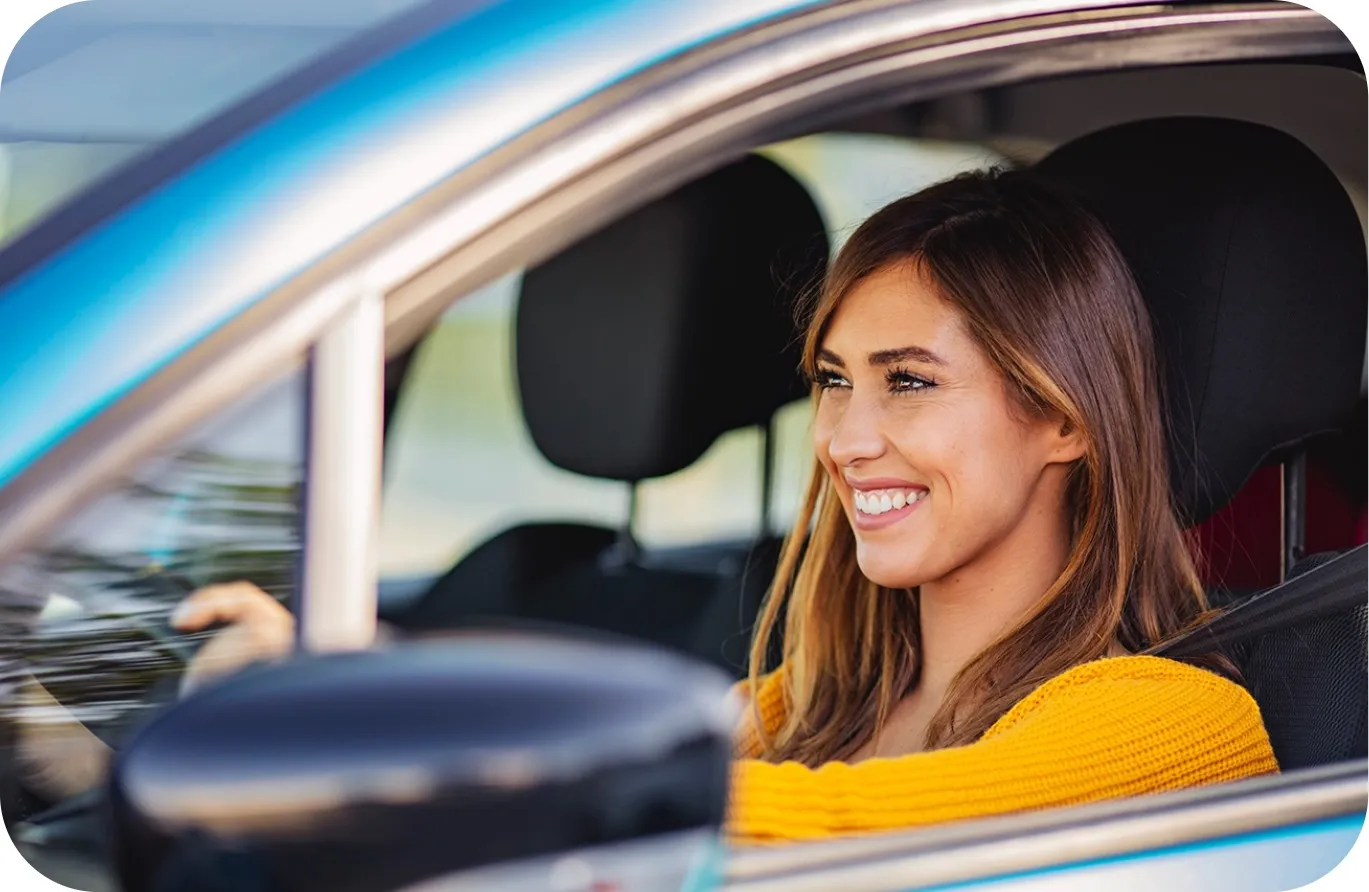Une conductrice souriante au volant de sa voiture